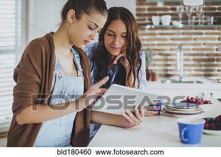 Caucasian women using digital tablet in kitchen View Large Photo Image Stock Image - Caucasian women using digital tablet in kitchen. Fotosearch