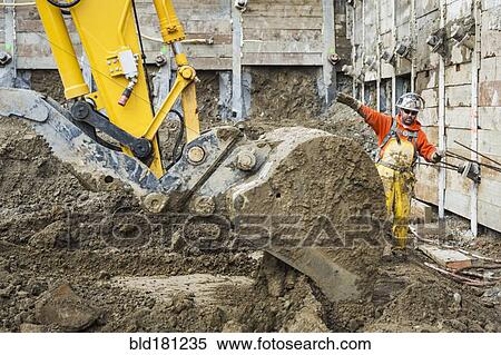 Caucasian worker directing digger at construction site View Large Photo Image Stock Photography - Caucasian worker directing digger at construction site. Fotosearch