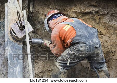 Picture - Caucasian worker drilling at construction site. Fotosearch