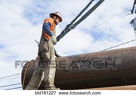 Caucasian worker hauling pipe at construction site View Large Photo Image Stock Photo - Caucasian worker hauling pipe at construction site. Fotosearch