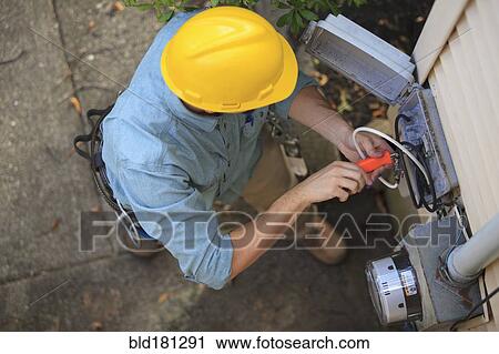 Stock Image - Caucasian worker installing cable box. Fotosearch