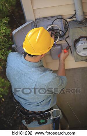 Stock Image - Caucasian worker installing cable box. Fotosearch