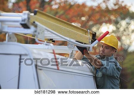 Stock Photo - Caucasian worker loading ladder on truck. Fotosearch