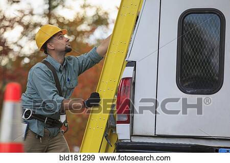 Stock Photo - Caucasian worker loading ladder on truck. Fotosearch