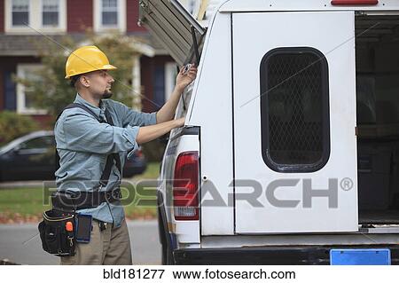 Stock Photo - Caucasian worker pulling equipment from truck. Fotosearch
