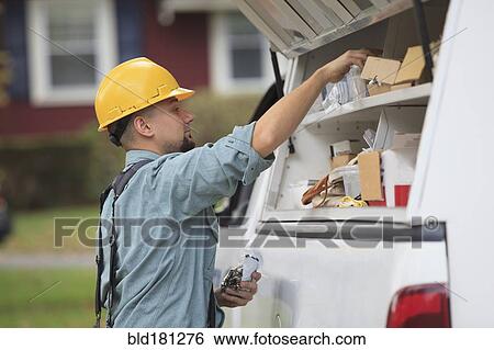 Stock Photograph - Caucasian worker pulling equipment from truck. Fotosearch