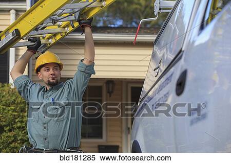 Stock Photography - Caucasian worker pulling ladder from truck roof. Fotosearch