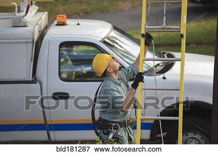 Stock Photo - Caucasian worker raising ladder outdoors. Fotosearch