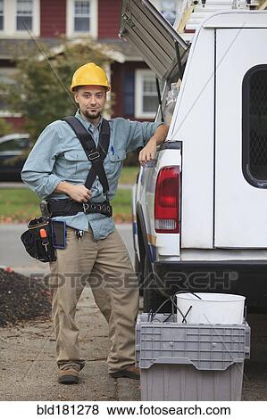 Stock Photo - Caucasian worker smiling at truck. Fotosearch