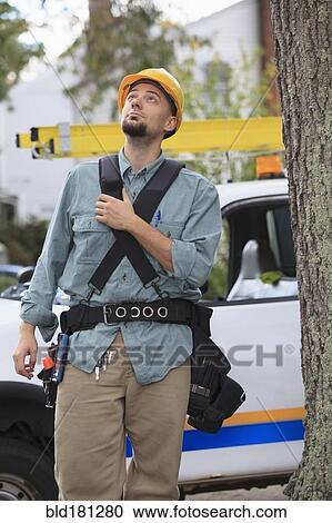 Stock Image - Caucasian worker walking under tree. Fotosearch