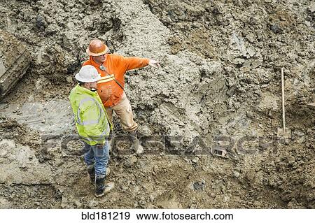 Caucasian workers talking at construction site View Large Photo Image Stock Photo - Caucasian workers talking at construction site. Fotosearch