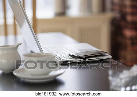 Cell phone and laptop on coffee shop table View Large Photo Image Stock Image - Cell phone and laptop on coffee shop table. Fotosearch