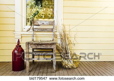 Stock Photo - Chair with dried leaves and jug on porch. Fotosearch