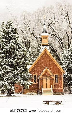 Stock Image - Church and bench in snowy field. Fotosearch