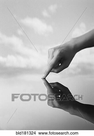 Picture - Close up of hand touching still water. Fotosearch