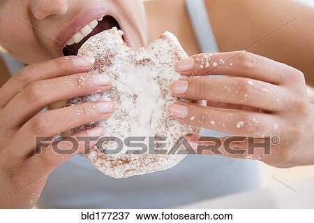 Stock Photo - Close up of Hispanic woman eating donut. Fotosearch