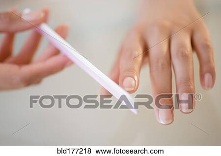 Stock Photo - Close up of Hispanic woman filing her nails. Fotosearch