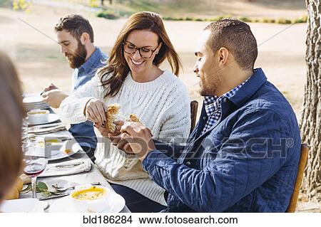 Picture - Couple breaking bread at outdoor table. Fotosearch