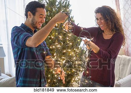 Stock Photo - Couple decorating Christmas tree. Fotosearch