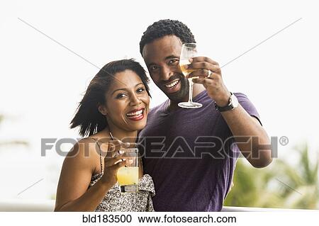 Stock Image - Couple drinking cocktails outdoors. Fotosearch
