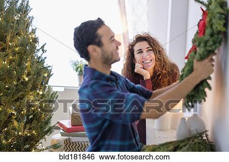 Stock Photograph - Couple hanging Christmas wreath. Fotosearch