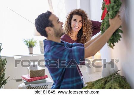Stock Photography - Couple hanging Christmas wreath. Fotosearch
