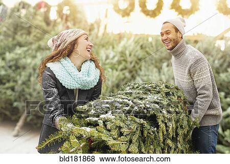 Stock Photo - Couple hauling tree at Christmas tree farm. Fotosearch