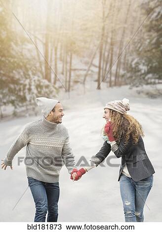 Stock Image - Couple holding hands in snow. Fotosearch