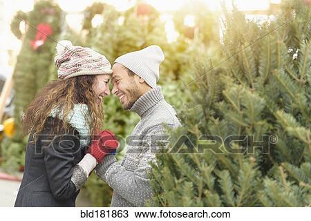 Stock Image - Couple hugging at Christmas tree farm. Fotosearch
