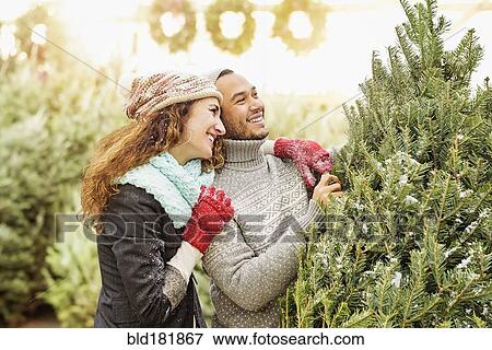 Stock Photo - Couple hugging at Christmas tree farm. Fotosearch