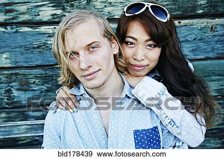 Stock Photo - Couple hugging at wooden wall. Fotosearch