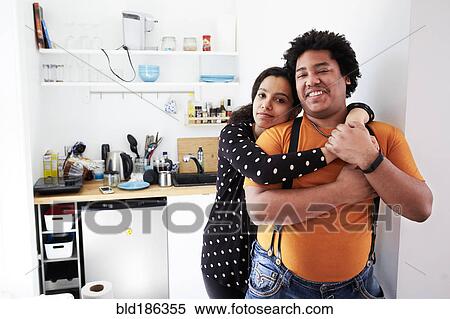 Stock Photography - Couple hugging in kitchen. Fotosearch