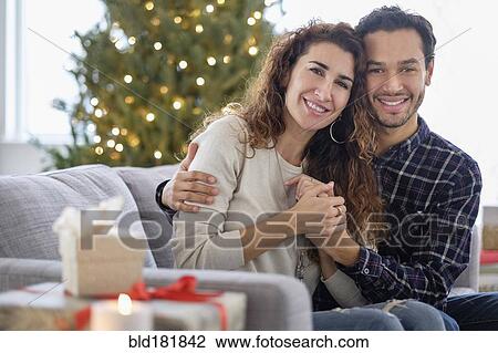 Stock Image - Couple hugging on sofa. Fotosearch