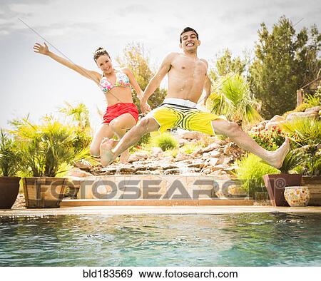 Stock Photo - Couple jumping into swimming pool. Fotosearch
