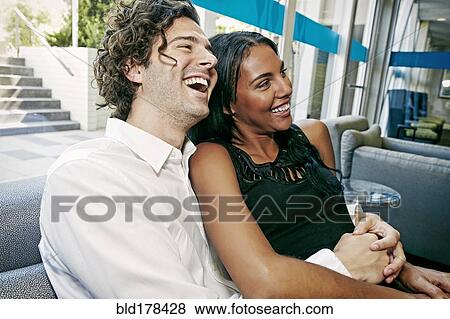 Couple laughing on sofa View Large Photo Image Stock Photo - Couple laughing on sofa. Fotosearch