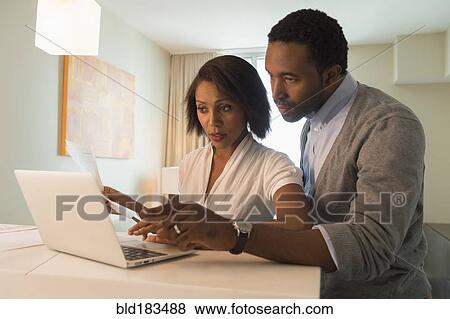 Couple paying bills on laptop View Large Photo Image Stock Photo - Couple paying bills on laptop. Fotosearch