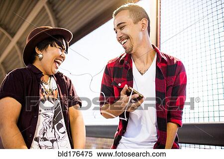 Stock Photography - Couple sharing earphones to listen to music. Fotosearch