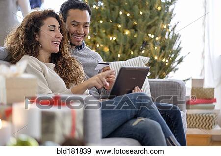 Stock Photo - Couple shopping with digital tablet on sofa. Fotosearch