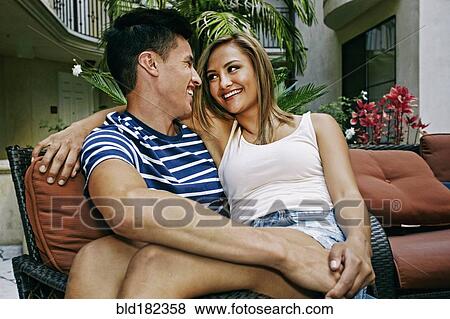 Stock Photo - Couple sitting on armchair in courtyard. Fotosearch
