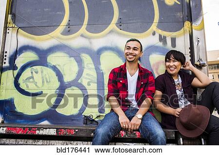 Stock Image - Couple sitting on graffiti truck. Fotosearch