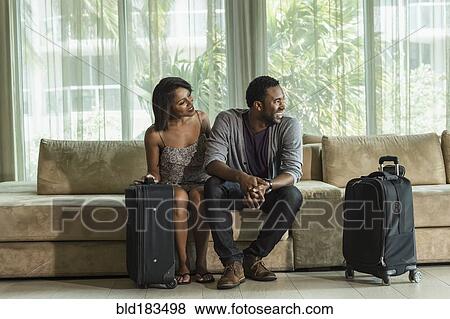 Stock Photo - Couple sitting on hotel lobby sofa. Fotosearch