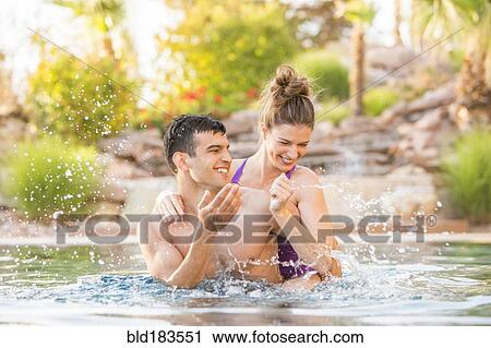 Couple splashing in swimming pool View Large Photo Image Stock Image - Couple splashing in swimming pool. Fotosearch