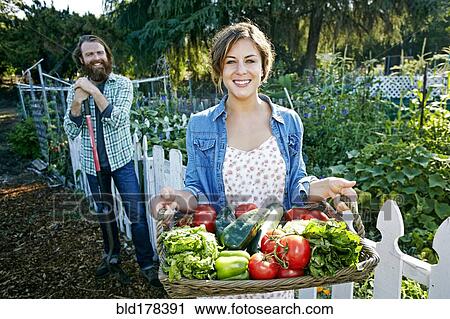 Couple standing with basket of vegetables in garden View Large Photo Image Stock Image - Couple standing with basket of vegetables in garden. Fotosearch