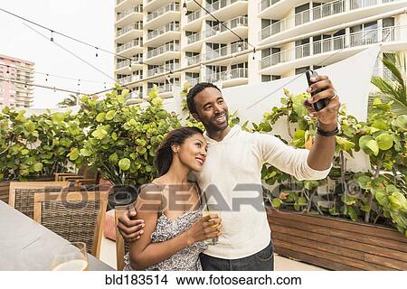 Picture - Couple taking selfie on urban rooftop. Fotosearch