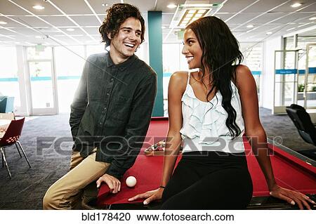 Stock Image - Couple talking at pool table. Fotosearch