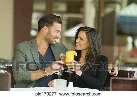 Couple toasting with cocktails at restaurant View Large Photo Image Stock Photo - Couple toasting with cocktails at restaurant. Fotosearch
