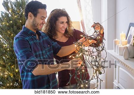 Couple untangling Christmas lights View Large Photo Image Stock Image - Couple untangling Christmas lights. Fotosearch