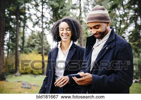 Stock Photo - Couple using cell phone in park. Fotosearch