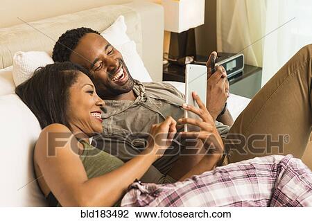 Couple using digital tablet on bed View Large Photo Image Stock Image - Couple using digital tablet on bed. Fotosearch