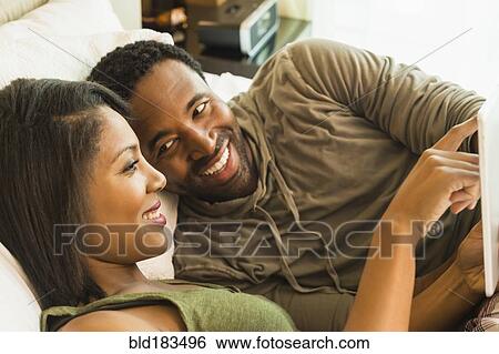 Couple using digital tablet on bed View Large Photo Image Stock Photograph - Couple using digital tablet on bed. Fotosearch